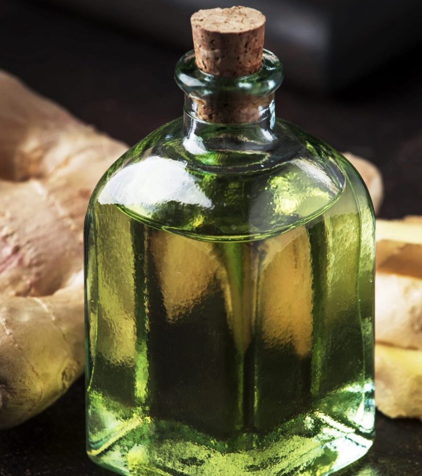 Ginger oil and fresh ginger root, dark table, selective focus