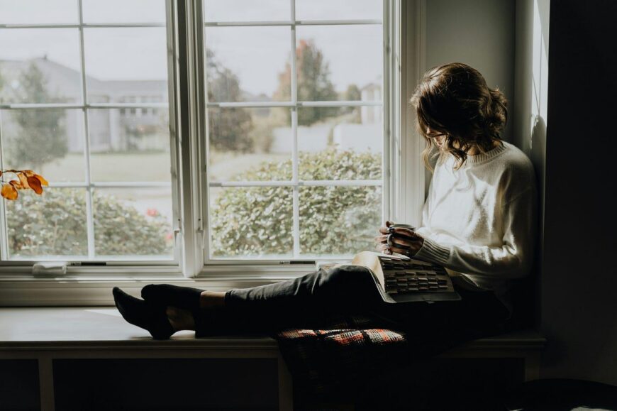 Midlife woman sitting by a window, managing sleep disturbances and perimenopause symptoms.