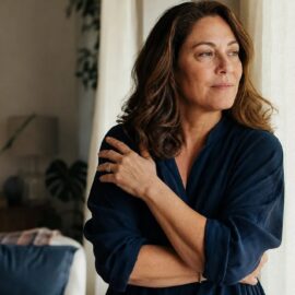 Midlife woman standing quietly in soft light, navigating the grief of not feeling like herself in menopause.