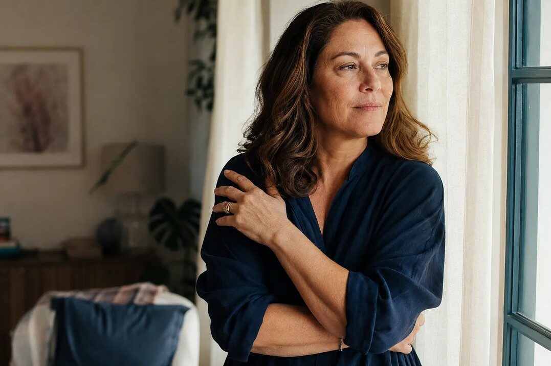 Midlife woman standing quietly in soft light, navigating the grief of not feeling like herself in menopause.