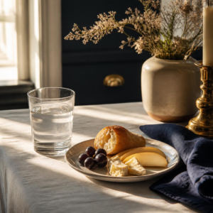 A glass of water and simple food on a sunlit table, representing steadiness over restriction for menopause bloating